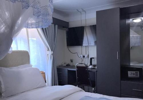 a bedroom with a bed and a desk and a window at Kaa Highway Hotel in Mukono
