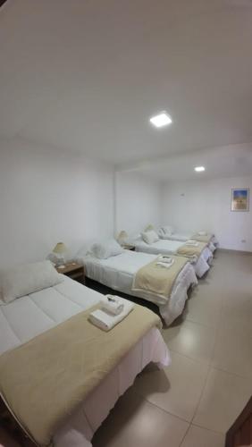 a row of four beds in a room at Cabañas Casa Blanca in El Mollar