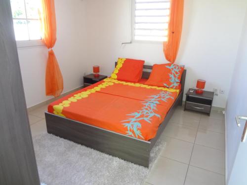 a bedroom with a bed with orange and yellow pillows at Villa Palulie in Capesterre-Belle-Eau