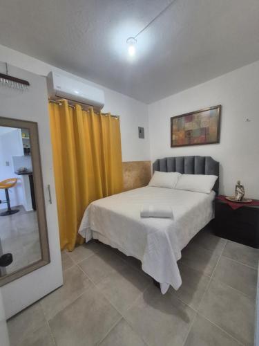 a bedroom with a large bed with yellow curtains at OMY Apartments Nagua 2A in Nagua