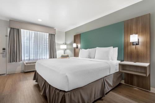 a large bed in a hotel room with a large window at Best Western Plus Riviera in Menlo Park