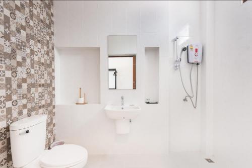 a white bathroom with a toilet and a sink at The Boutique Khanom in Khanom
