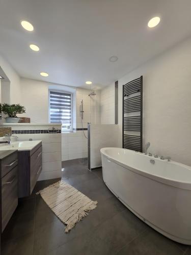 a bathroom with a large white tub and a sink at Rosenzauber Seeromantik "Kramer" in Weißenstadt