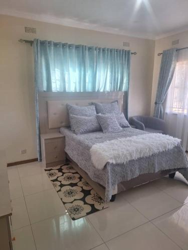 a bedroom with a large bed with blue curtains at The Cave at 55 St Patricks in Harare