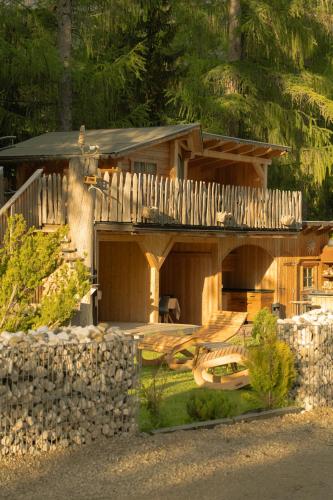 a log cabin with a porch and a stone wall at Planat in San Cassiano