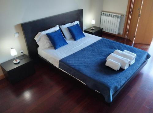 a bedroom with a large bed with blue pillows and towels at Single House in Vila Real