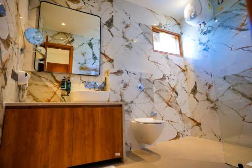 a bathroom with a marble wall with a sink and a toilet at The ELET near Amritsar Airport in Amritsar