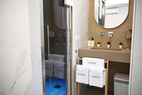 a bathroom with a sink and a mirror and towels at Kleos Luxury Rooms in Porto Empedocle