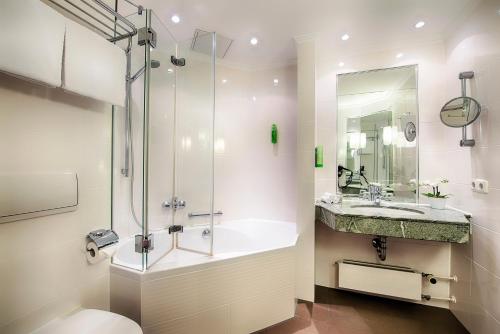 a bathroom with a tub and a sink and a shower at Welcome Hotel Residenzschloss Bamberg in Bamberg