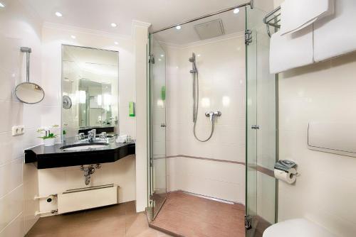 a bathroom with a glass shower and a sink at Welcome Hotel Residenzschloss Bamberg in Bamberg