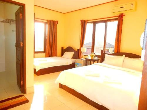 a hotel room with two beds and a window at Camellia Vang Vieng in Vang Vieng