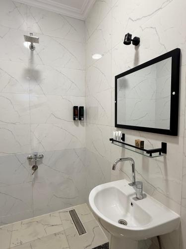 a white bathroom with a sink and a mirror at El Bawaba Lodge & Luxury Retreat in Luxor