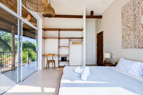 a bedroom with a bed and a large window at Beachfront Dream in Ban Tai in Ban Tai