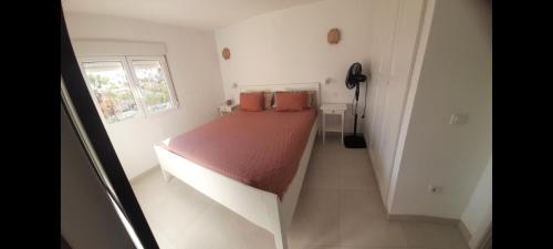 a small white room with a bed with a red blanket at TORRES DEL SOL A 50 metros playa las vistas in Playa de las Americas