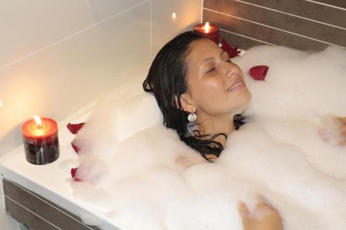 a woman laying in a bath tub with candles at Business Class Prims Hotel in Jaén