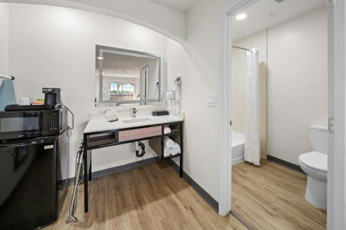 a bathroom with a sink and a mirror and a toilet at Ramada by Wyndham Ontario Airport & Convention Center in Ontario