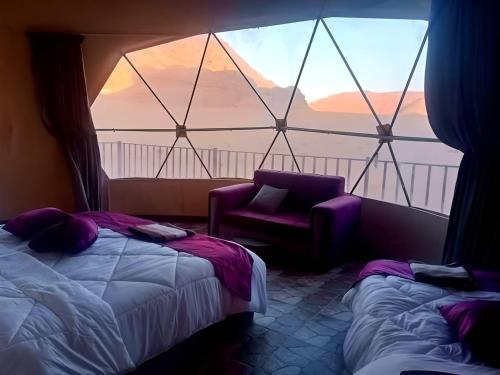 a room with a bed and a chair and a window at Wadi rum bubble camp in Wadi Musa