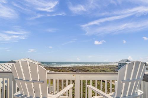 two white chairs sitting on a porch looking at the ocean at The White House in Padre Island