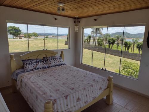 a bedroom with a bed and windows with a view at Refúgio do Jaguari in Piracaia
