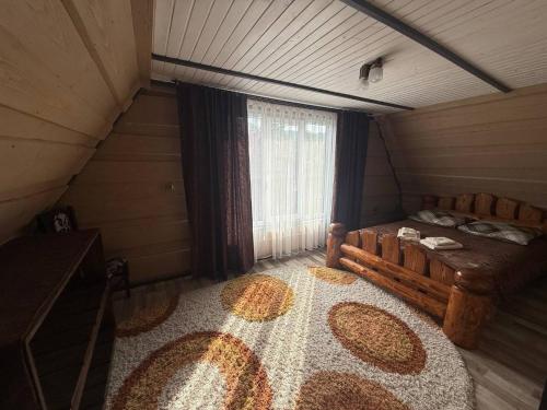 an attic room with a large bed and a window at Горянка in Oryava