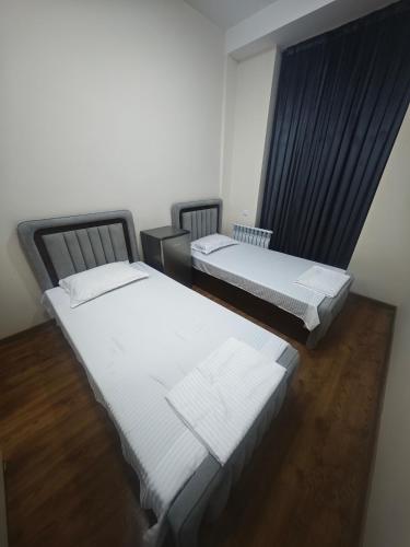 two twin beds in a room with wooden floors at Baxt Hotel&Hostel in Andijan