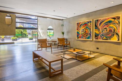 a living room with a table and a painting on the wall at Intercity Faria Lima Address in São Paulo