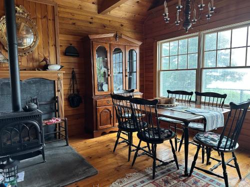 a dining room with a table and chairs and a fireplace at Capstone Cottage - Quintessential Cabin on Bay in Gouldsboro