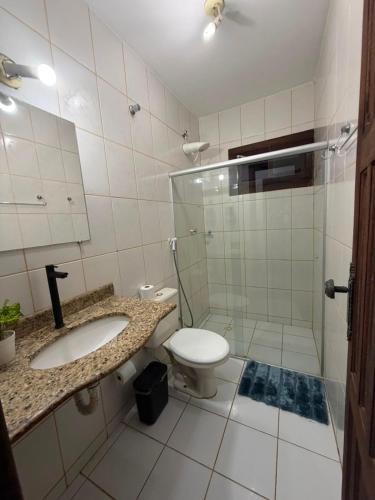 a bathroom with a toilet and a sink and a shower at Refúgio a 100m da Praia Conforto e Lazer Completo in Prado