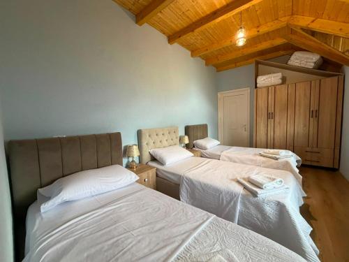 two beds in a room with wooden ceilings at Villa Bushati in Tropojë
