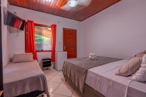 a bedroom with two beds and a window with red curtains at BLUE DOOR BRASIL in Abraão