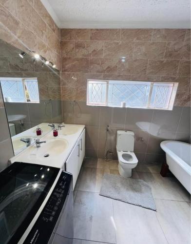 a bathroom with a sink and a toilet and a tub at BillGates BNB in Harare