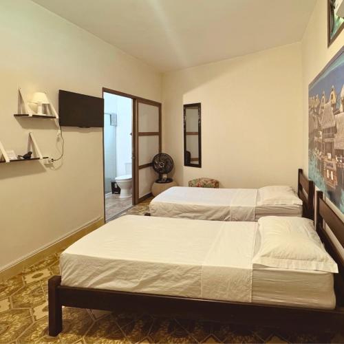 a bedroom with two beds and a tv at Tombo Beach Home Stay in Guarujá