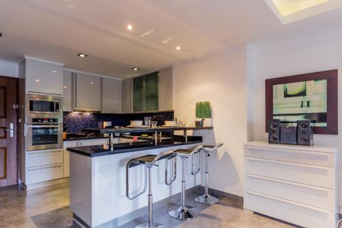 a kitchen with white cabinets and a counter with stools at Dasiri Beach Apartment Premium in North Pattaya