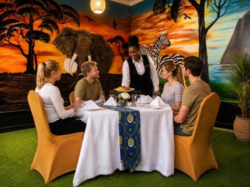 a group of people sitting around a table in a restaurant at La Planete Hotel in Rubavu
