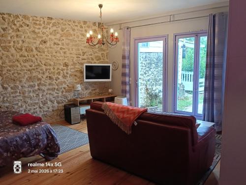 a living room with a couch and a tv at La Cadournaise in Saint-Seurin-de-Cadourne