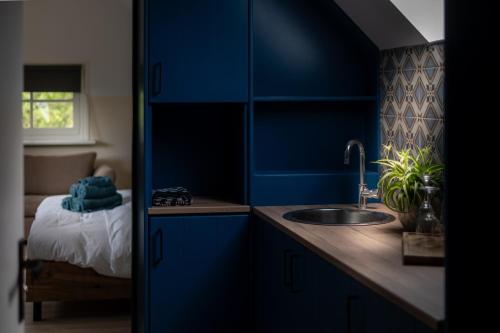 a blue kitchen with a sink and a bed at Maison Bienvenue in Lierop