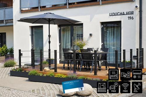 a table with an umbrella in front of a building at ENJOYHARRACHOV - Atraktivní slunný klimatizovaný apartmán 24 v centru Harrachova s velkou terasou, saunou, parkováním, Wifi-WLAN, SAT, herní konzolí, Netflix zdarma a možností dobíjení auta jen 150m od lanovky in Harrachov
