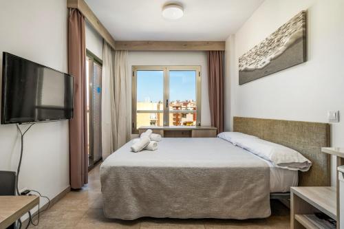 a hotel room with a bed and a flat screen tv at Marina Beach Apartaments - Sea views in the heart of Lloret in Lloret de Mar