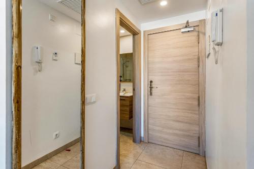 a bathroom with a wooden door and a mirror at Marina Beach Apartaments - Sea views in the heart of Lloret in Lloret de Mar