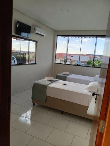 a bedroom with two beds and two windows at Pousada Panorama Palace in Santa Maria da Vitória