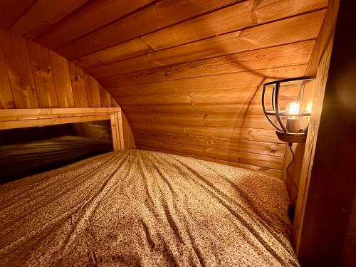 a small bedroom with a bed in a wooden room at Barrel de Verreblik in Pieterburen