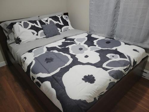 a bed with a black and white comforter with flowers at Private 2 bedroom suite close to everything! in Maple Ridge