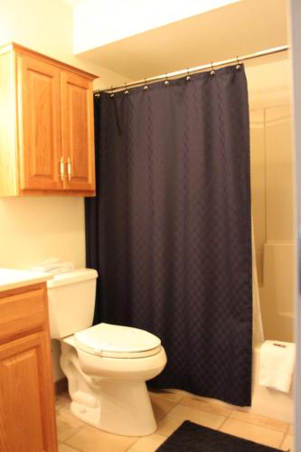 a bathroom with a toilet and a black shower curtain at Nordic Inn Condominium Resort in Lincoln