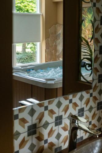 a bathroom with a tub with a sink and a mirror at Maison Bienvenue in Lierop