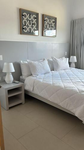a bed with white sheets and pillows in a bedroom at Blue Coast Condo in Puerto Plata