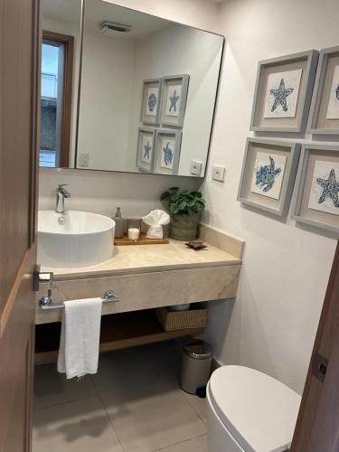 a bathroom with a sink and a mirror and a toilet at Blue Coast Condo in Puerto Plata