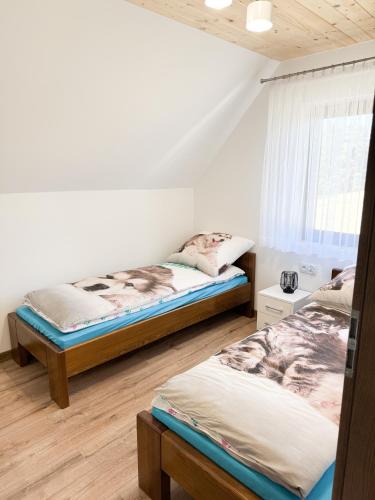 a bedroom with two beds and a window at Agroturystyka Nad Lasem - Domki w górach in Toporzysko