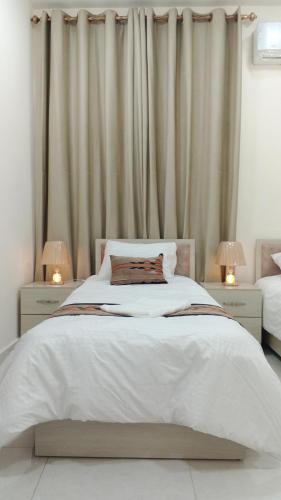 a bedroom with a large white bed with two lamps at انوار عمان - Anwar Amman Hotel in Amman