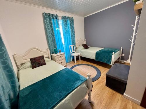 two beds in a room with blue curtains at Casa das Courelas in Nordeste
