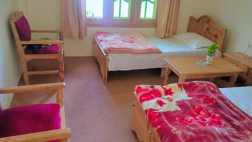 a room with two beds and a table and a chair at Ibrahim lodge restaurant in Astor